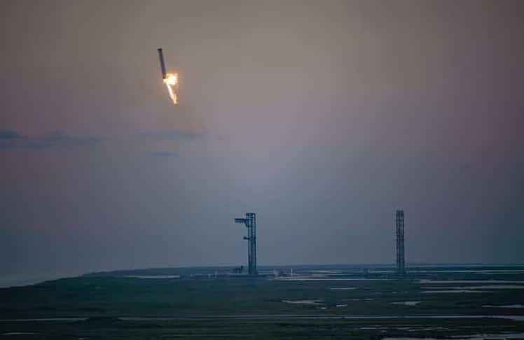 Der rund 70 Meter hohe Super Heavy Booster beim Landeanflug auf "Mechazilla" in Texas (Bild: SpaceX / Elon Musk auf X)