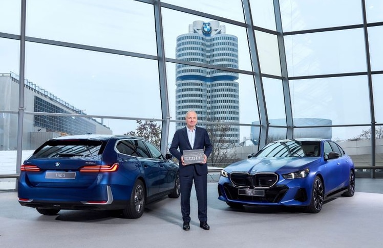 Jochen Goller, Vorstand für Kunde, Marken und Vertrieb bei der BMW AG, mit dem "German Car of the Year 2025“-Award – im Hintergrund die BMW 5er Modelle, die den Sieg errangen. © BMW Group