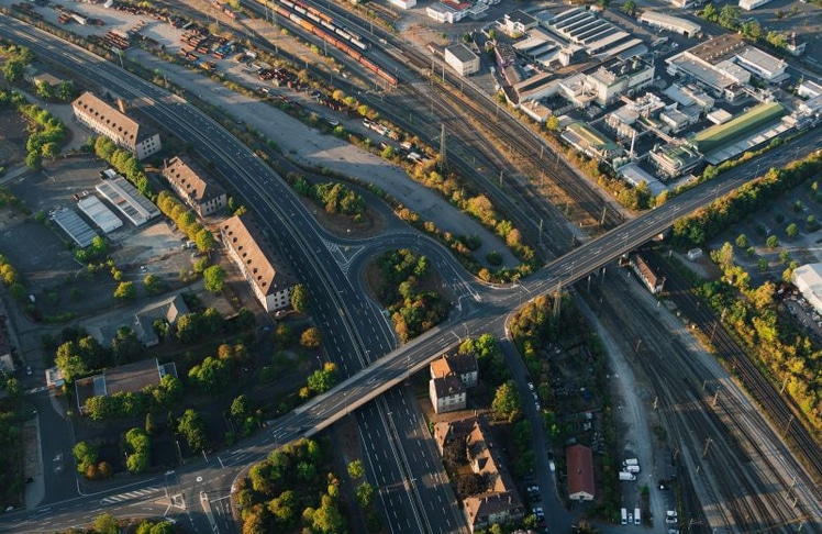 Luftaufnahme eines Verkehrsknotens mit Straßen und Bahninfrastruktur – ein Symbol für den dringenden Investitionsbedarf in Deutschlands Verkehrswege. Das 500-Milliarden-Euro-Programm soll solche Knotenpunkte modernisieren und die Infrastruktur nachhaltig verbessern.